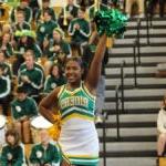 Two cheerleaders in Roosevelt school colors of green and gold lead a crowd in cheer